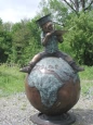 Boy sitting on world reading bronze statue